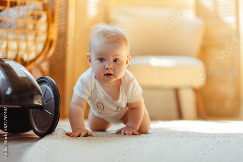 Adorable baby crawling on floor in living room at home. Beautiful child growing. Development concept photo