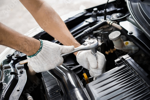 Close-up of male mechanic hand in glove holding wrench to repair or maintain engine. male hand holding a wrench  Car repair and inspection. car maintenance concept © MrAnuwat