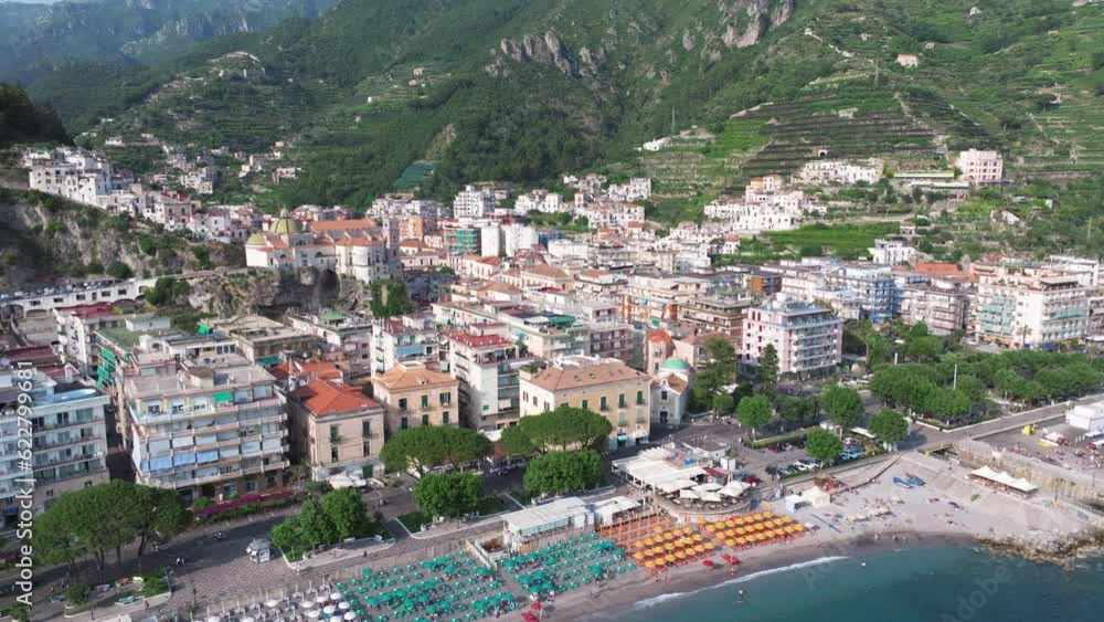 Aerial view of a modern beach with many chairs and umbrellas in Maiori, Italy. Top drone view of people relaxing by a huge coastal beach with clean transparent turquoise Mediterranean water in Amalfi