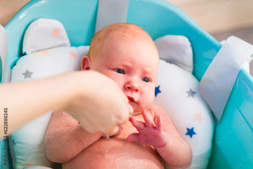 A newborn baby takes a bath. A lovely child is undergoing military
