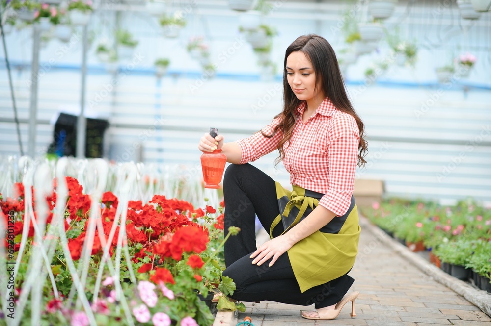 Woman florist working at her flower shop standing surrounded by plants