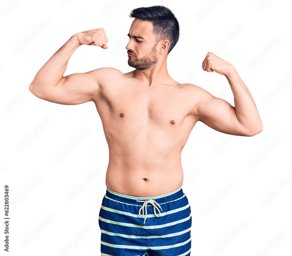 Young handsome man wearing swimwear showing arms muscles smiling proud. fitness concept. Young handsome man wearing swimwear showing arms muscles smiling proud. fitness concept.