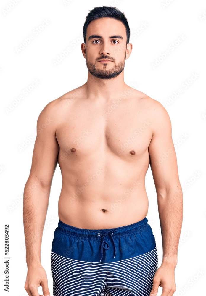 Young handsome man wearing swimwear with serious expression on face. simple and natural looking at the camera. Young handsome man wearing swimwear with serious expression on face. simple and natural looking at the camera.