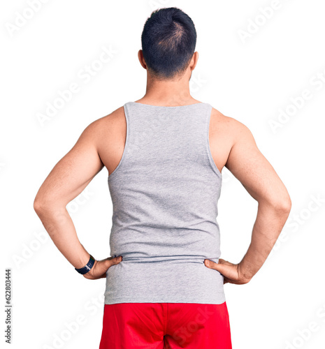 Картината върху платно Young handsome man wearing swimwear and sleeveless t-shirt standing backwards lo
