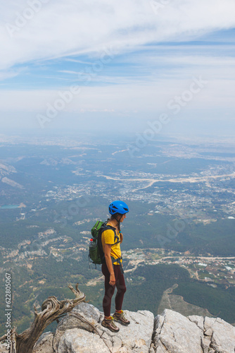 climber with a backpack and a helmet stands on top of the mountain. Girl climber in the mountains. adventure and mountaineering concept.