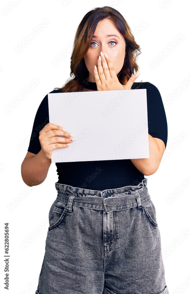 Young beautiful caucasian woman holding blank empty paper covering mouth with hand, shocked and afraid for mistake. surprised expression Young beautiful caucasian woman holding blank empty paper covering mouth with hand, shocked and afraid for mistake. surprised expression