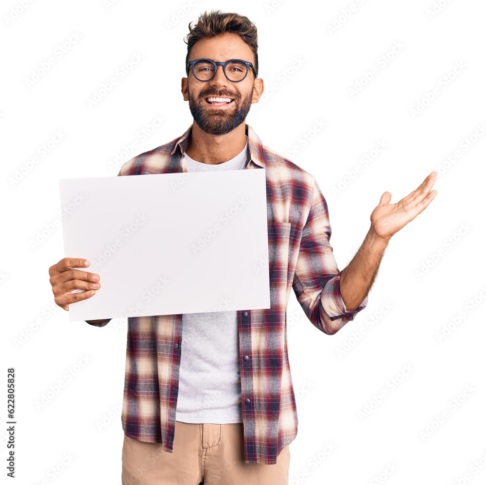 Young hispanic man holding blank empty banner celebrating victory with happy smile and winner expression with raised hands Young hispanic man holding blank empty banner celebrating victory with happy smile and winner expression with raised hands