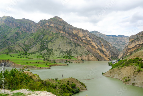 The landscape of the Caucasus Mountains river on the background of a blue sky with clouds.