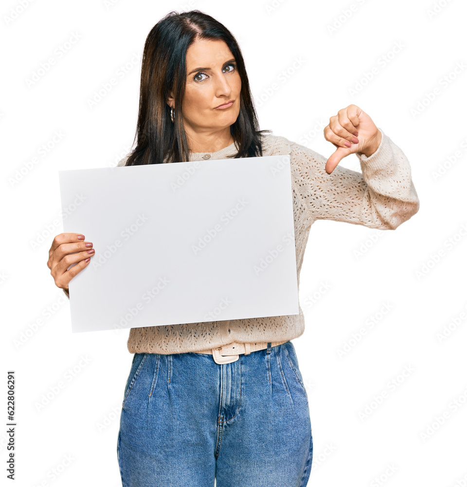 Middle age brunette woman holding blank empty banner with angry face, negative sign showing dislike with thumbs down, rejection concept Middle age brunette woman holding blank empty banner with angry face, negative sign showing dislike with thumbs down, rejection concept