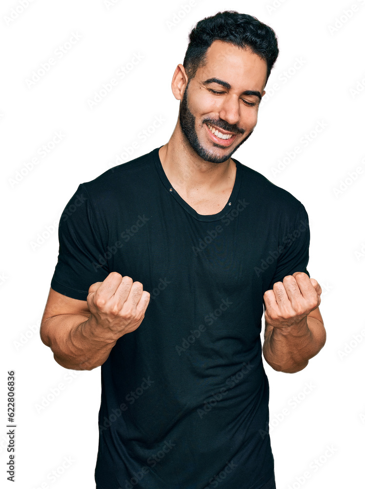 Hispanic man with beard wearing casual black t shirt very happy and excited doing winner gesture with arms raised, smiling and screaming for success. celebration concept. Hispanic man with beard wearing casual black t shirt very happy and excited doing winner gesture with arms raised, smiling and screaming for success. celebration concept.