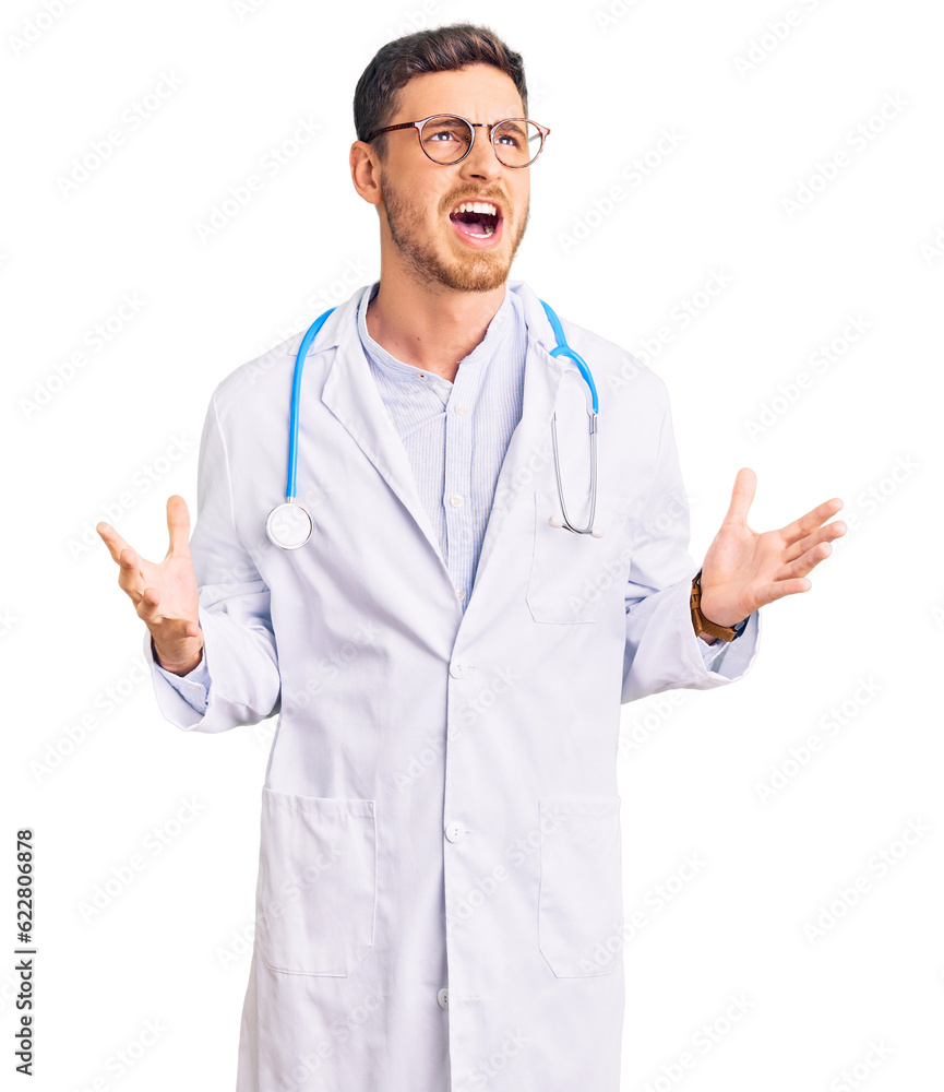 Handsome young man with bear wearing doctor uniform crazy and mad shouting and yelling with aggressive expression and arms raised. frustration concept. Handsome young man with bear wearing doctor uniform crazy and mad shouting and yelling with aggressive expression and arms raised. frustration concept.