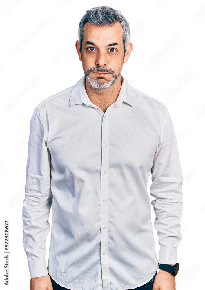 Middle age hispanic with grey hair wearing casual white shirt puffing cheeks with funny face. mouth inflated with air, crazy expression. Middle age hispanic with grey hair wearing casual white shirt puffing cheeks with funny face. mouth inflated with air, crazy expression.