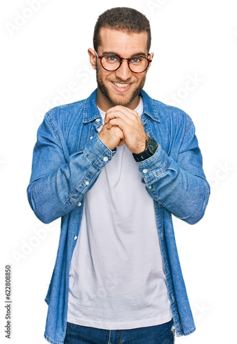Young caucasian man wearing casual clothes laughing nervous and excited with hands on chin looking to the side