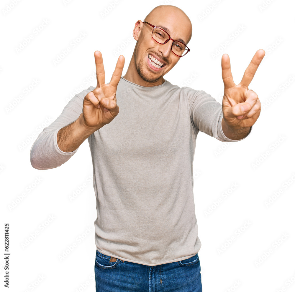 Bald man with beard wearing casual clothes and glasses smiling looking to the camera showing fingers doing victory sign. number two. Bald man with beard wearing casual clothes and glasses smiling looking to the camera showing fingers doing victory sign. number two.