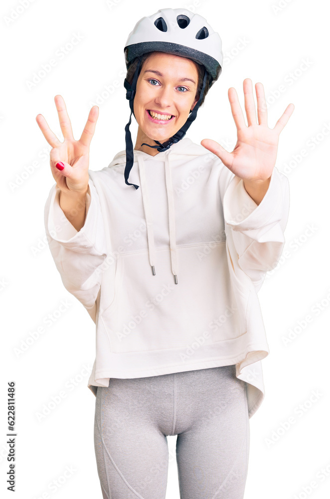 Beautiful brunette young woman wearing bike helmet and sporty clothes showing and pointing up with fingers number eight while smiling confident and happy. Beautiful brunette young woman wearing bike helmet and sporty clothes showing and pointing up with fingers number eight while smiling confident and happy.