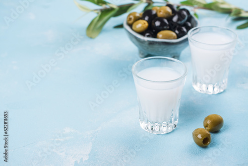 Traditional greek vodka ouzo and marinated olives on blue slate background. Copy space