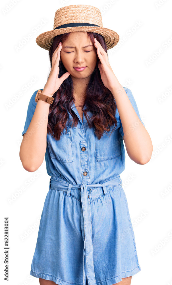 Young beautiful chinese girl wearing summer hat with hand on head, headache because stress. suffering migraine. Young beautiful chinese girl wearing summer hat with hand on head, headache because stress. suffering migraine.