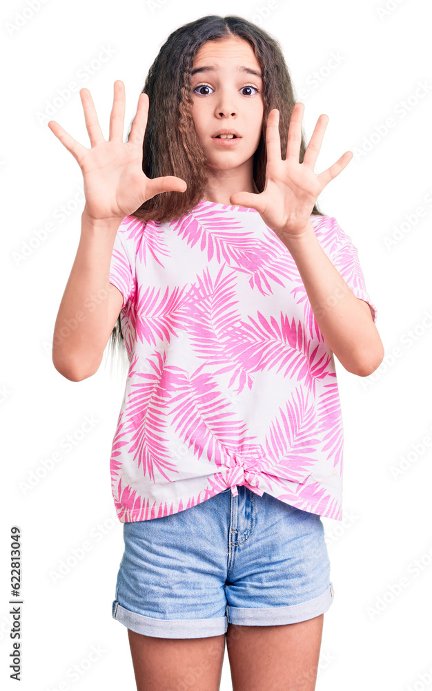 Cute hispanic child girl wearing casual clothes afraid and terrified with fear expression stop gesture with hands, shouting in shock. panic concept.