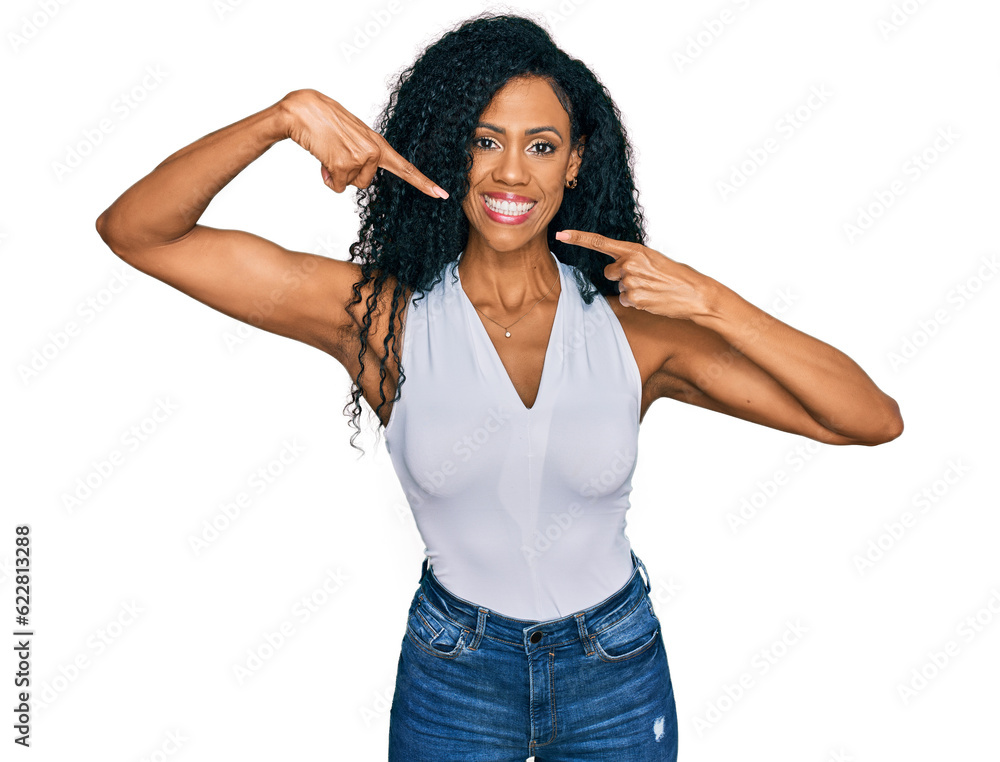Middle age african american woman wearing casual style with sleeveless shirt smiling cheerful showing and pointing with fingers teeth and mouth. dental health concept. Middle age african american woman wearing casual style with sleeveless shirt smiling cheerful showing and pointing with fingers teeth and mouth. dental health concept.
