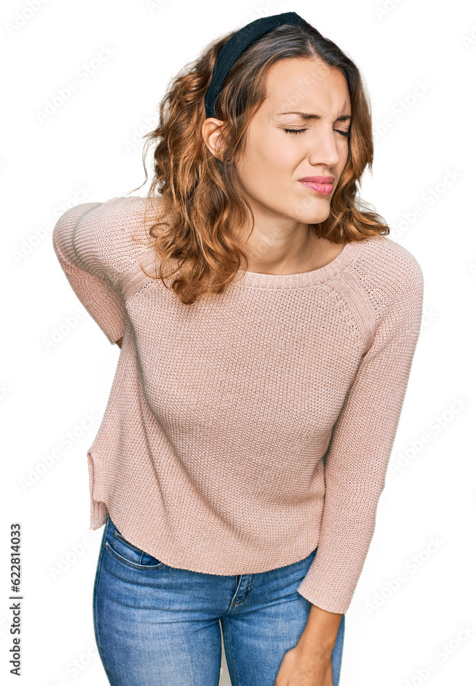 Beautiful young caucasian woman wearing casual sweater suffering of backache, touching back with hand, muscular pain Beautiful young caucasian woman wearing casual sweater suffering of backache, touching back with hand, muscular pain
