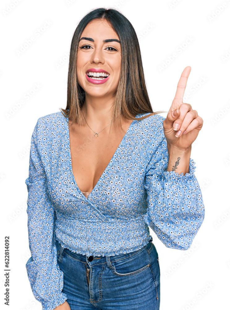 Young hispanic woman wearing casual clothes showing and pointing up with finger number one while smiling confident and happy. Young hispanic woman wearing casual clothes showing and pointing up with finger number one while smiling confident and happy.