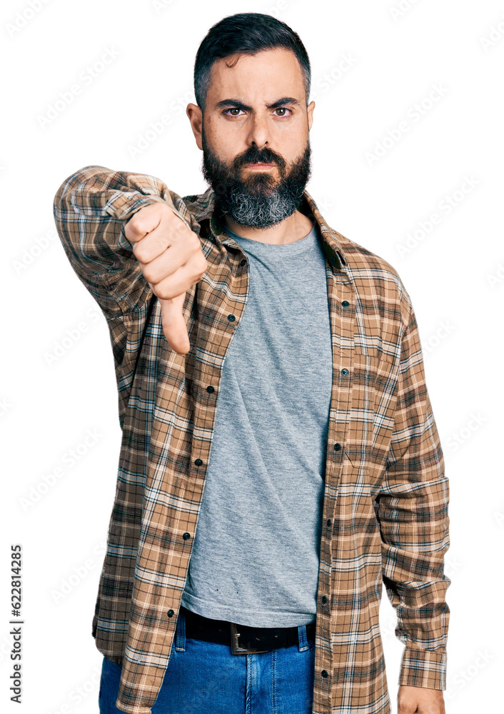 Hispanic man with beard wearing casual shirt looking unhappy and angry showing rejection and negative with thumbs down gesture. bad expression. Hispanic man with beard wearing casual shirt looking unhappy and angry showing rejection and negative with thumbs down gesture. bad expression.