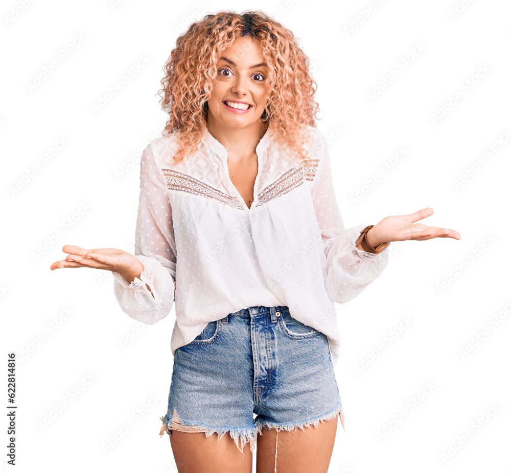 Young blonde woman with curly hair wearing elegant summer shirt clueless and confused expression with arms and hands raised. doubt concept. Young blonde woman with curly hair wearing elegant summer shirt clueless and confused expression with arms and hands raised. doubt concept.