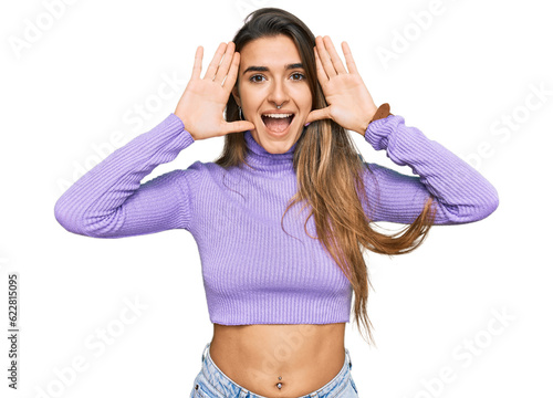 Young hispanic woman wearing casual clothes smiling cheerful playing peek a boo with hands showing face. surprised and exited photo