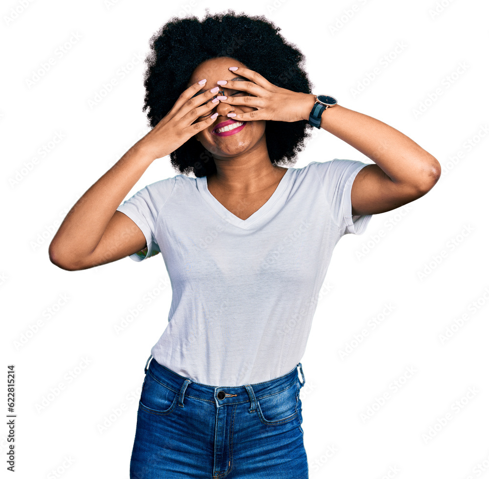 Young african american woman wearing casual white t shirt covering eyes with hands smiling cheerful and funny. blind concept. Young african american woman wearing casual white t shirt covering eyes with hands smiling cheerful and funny. blind concept.