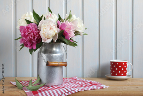 Fototapeta Naklejka Na Ścianę i Meble -  A bouquet of peonies in an aluminum can on a wooden table.