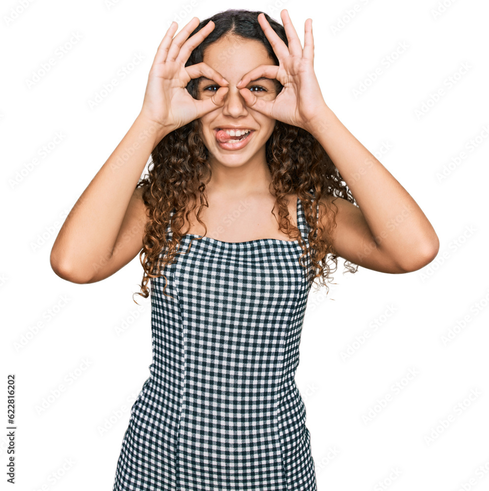Teenager hispanic girl wearing casual clothes doing ok gesture like binoculars sticking tongue out, eyes looking through fingers. crazy expression. Teenager hispanic girl wearing casual clothes doing ok gesture like binoculars sticking tongue out, eyes looking through fingers. crazy expression.