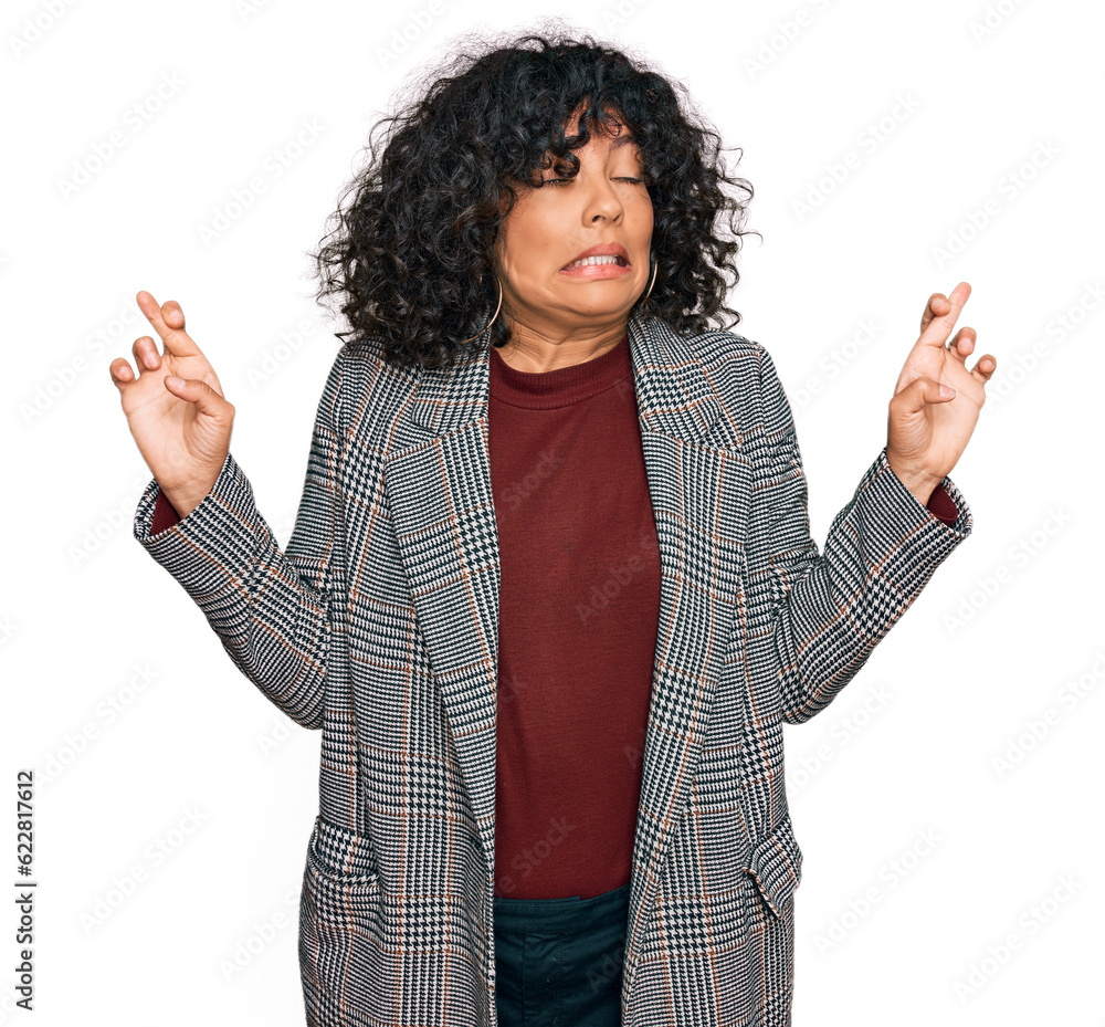 Young hispanic woman wearing business clothes gesturing finger crossed smiling with hope and eyes closed. luck and superstitious concept. Young hispanic woman wearing business clothes gesturing finger crossed smiling with hope and eyes closed. luck and superstitious concept.
