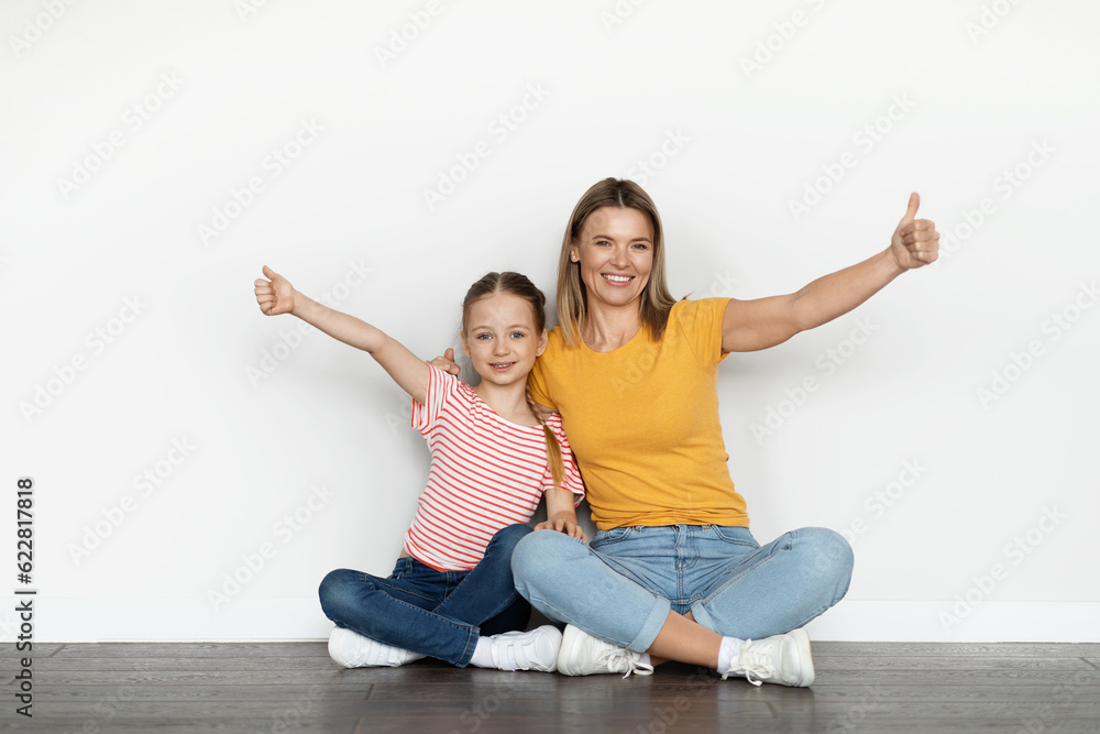 Happy Beautiful Young Mom And Little Daughter Embracing And Showing Thumbs Up Happy Beautiful Young Mom And Little Daughter Embracing And Showing Thumbs Up