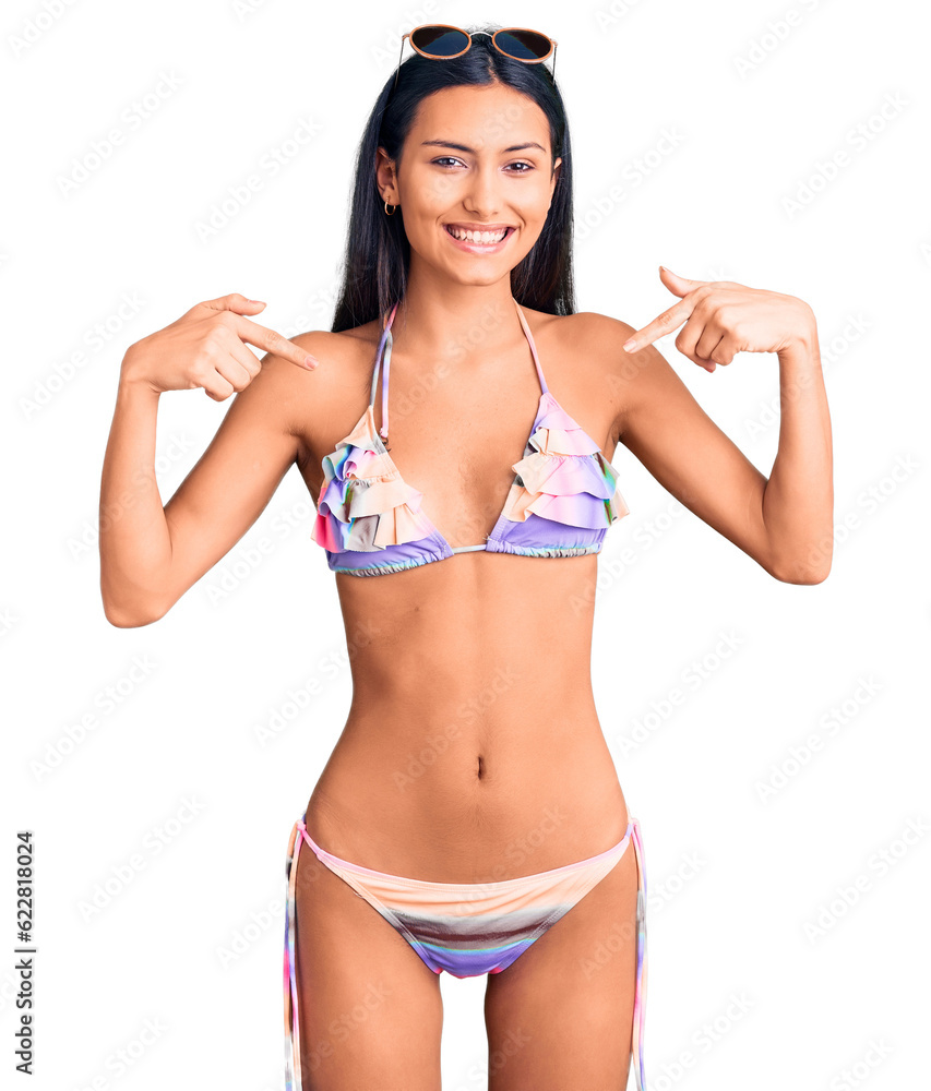 Young beautiful latin girl wearing bikini and sunglasses looking confident with smile on face, pointing oneself with fingers proud and happy. Young beautiful latin girl wearing bikini and sunglasses looking confident with smile on face, pointing oneself with fingers proud and happy.