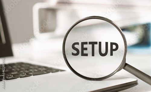 Text SETUP on magnifying glass on an office desk. Business concept for the analysisner, position, or direction in which something is set photo