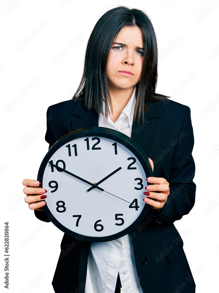 Young brunette woman with blue eyes holding big clock skeptic and nervous, frowning upset because of problem. negative person. Young brunette woman with blue eyes holding big clock skeptic and nervous, frowning upset because of problem. negative person.