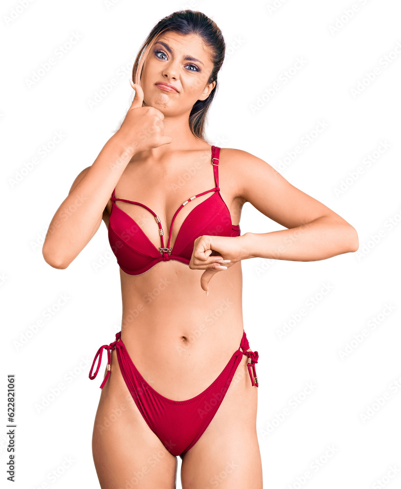 Young beautiful woman wearing bikini doing thumbs up and down, disagreement and agreement expression. crazy conflict Young beautiful woman wearing bikini doing thumbs up and down, disagreement and agreement expression. crazy conflict