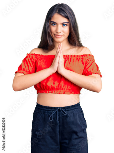 Brunette teenager girl wearing casual clothes praying with hands together asking for forgiveness smiling confident. © Krakenimages.com