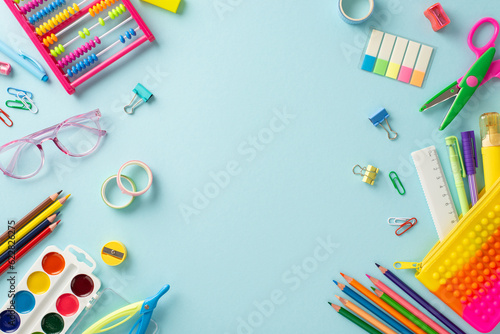 Dive into the world of early education with this top-down perspective: an assortment of bright school supplies set against a serene pastel blue backdrop, offering copyspace for text or advertisements