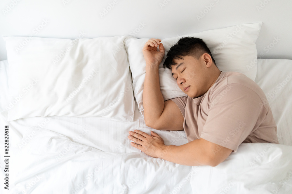 Top view of peaceful asian man sleeping in comfy bed Top view of peaceful asian man sleeping in comfy bed