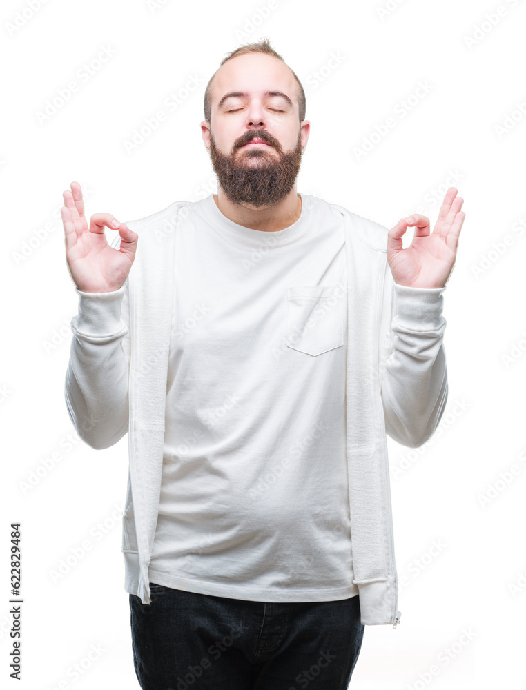 Young caucasian hipster man wearing sport clothes over isolated background relax and smiling with eyes closed doing meditation gesture with fingers. Yoga concept. Young caucasian hipster man wearing sport clothes over isolated background relax and smiling with eyes closed doing meditation gesture with fingers. Yoga concept.