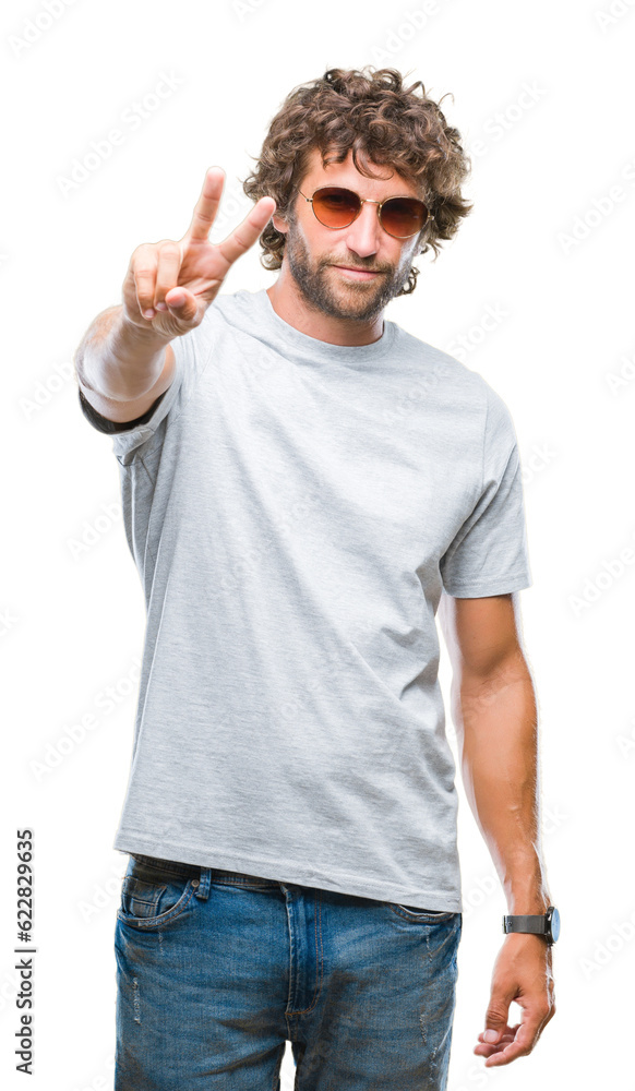 Handsome hispanic model man wearing sunglasses over isolated background smiling with happy face winking at the camera doing victory sign. Number two. Handsome hispanic model man wearing sunglasses over isolated background smiling with happy face winking at the camera doing victory sign. Number two.