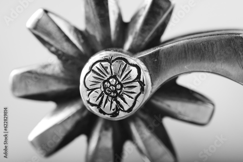 Western spur rowel with flower engraved on metal closeup in black and white.
