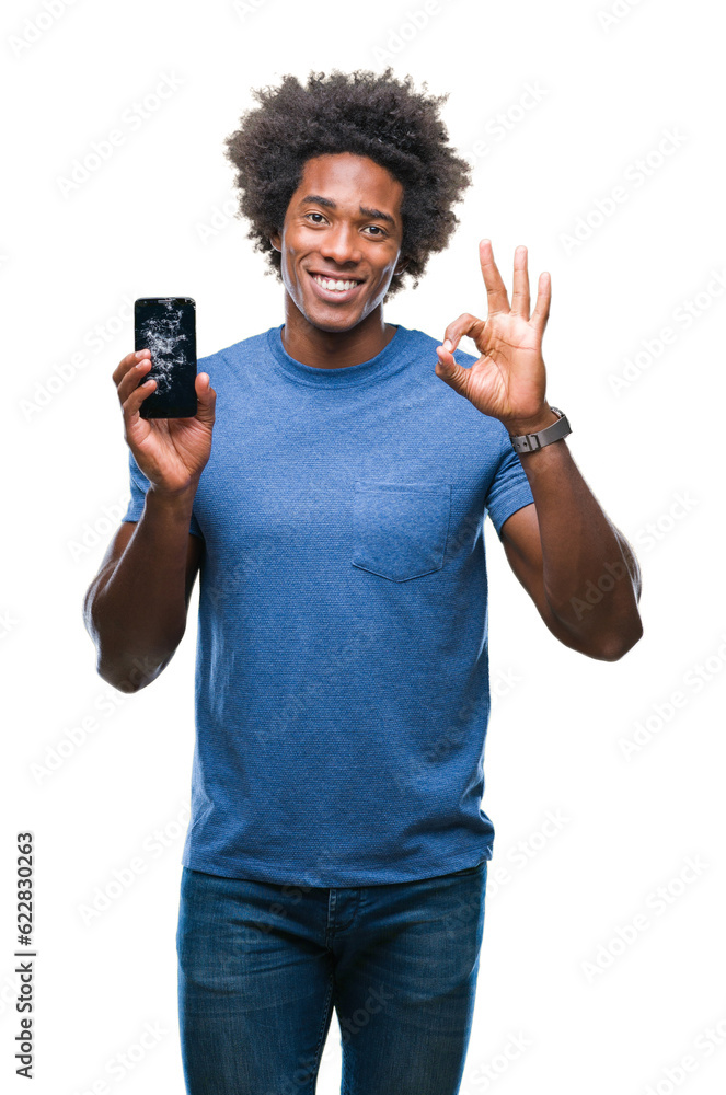 Afro american man holding broken smartphone over isolated background doing ok sign with fingers, excellent symbol Afro american man holding broken smartphone over isolated background doing ok sign with fingers, excellent symbol
