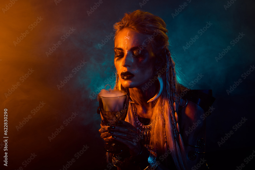 Photo of north mythology wizard viking girl hand hold potion cup orange blue lights mist isolated on dark background