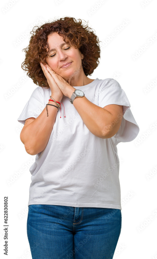 Beautiful middle ager senior woman wearing white t-shirt over isolated background sleeping tired dreaming and posing with hands together while smiling with closed eyes. Beautiful middle ager senior woman wearing white t-shirt over isolated background sleeping tired dreaming and posing with hands together while smiling with closed eyes.