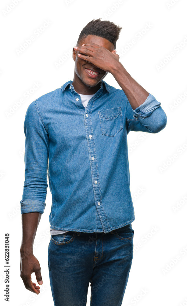 Young african american man over isolated background smiling and laughing with hand on face covering eyes for surprise. Blind concept. Young african american man over isolated background smiling and laughing with hand on face covering eyes for surprise. Blind concept.