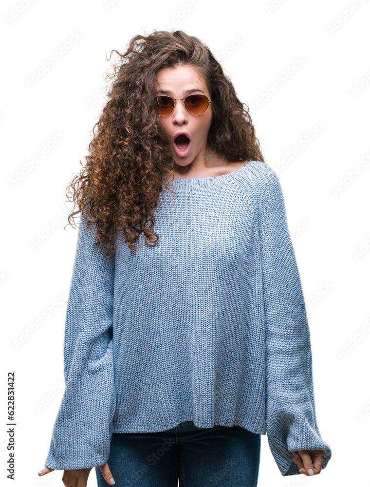 Beautiful brunette curly hair young girl wearing sunglasses over isolated background afraid and shocked with surprise expression, fear and excited face. Beautiful brunette curly hair young girl wearing sunglasses over isolated background afraid and shocked with surprise expression, fear and excited face.