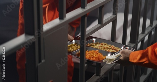 Obraz na płótnie Elderly prisoner in orange uniform sits in prison cell