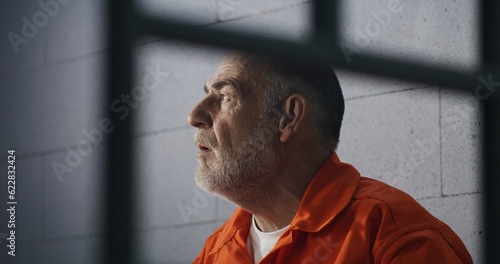 Cuadro en lienzo Elderly criminal in orange uniform sits on prison bed and dreams about freedom